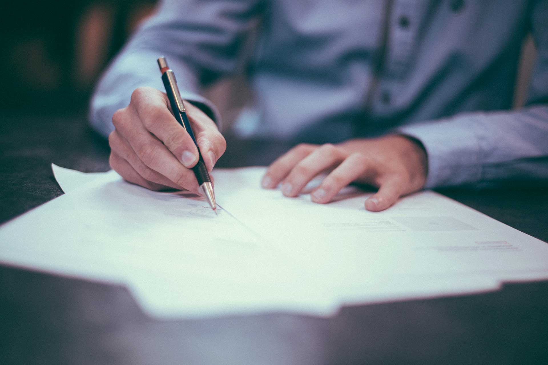 close up photo of a business man in a blue shirt signing a document