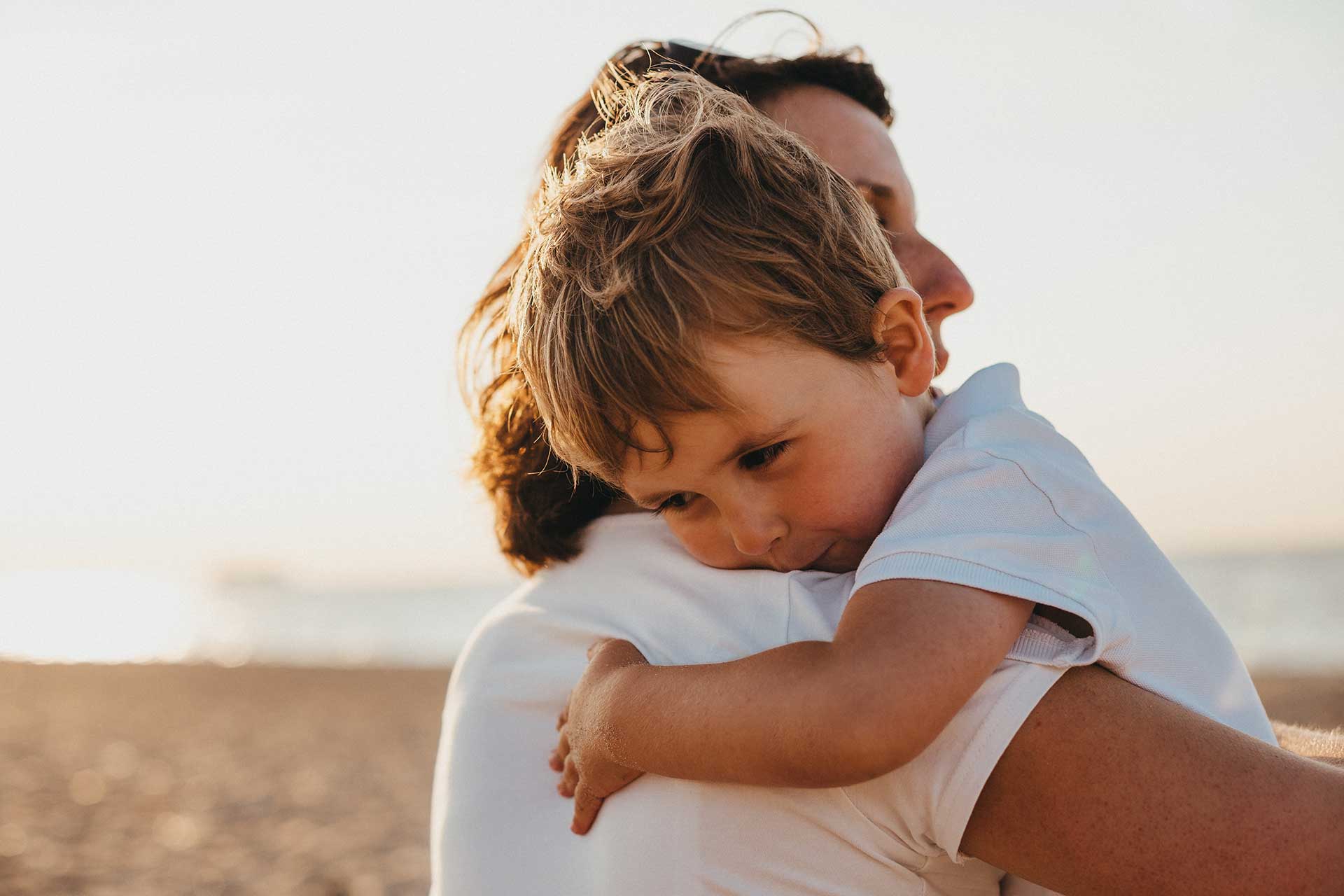 mother holding her child in her arms on a beach